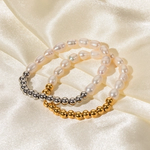 Gros plan de perles baroques et perles dorées 16K sur un tissu en soie champagne soyeux