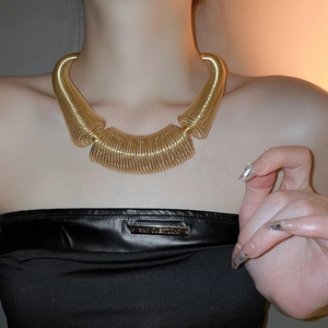 Chunky gold metal spring necklace in industrial style on a model with black top