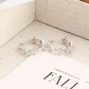Close-up of S925 silver hoop earrings with clover-shaped diamonds in a jewelry box