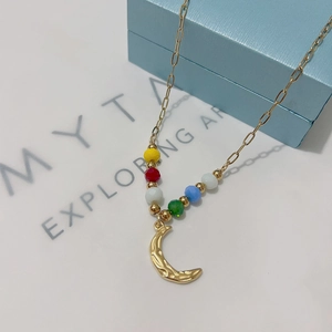Macro view of a 18k gold moon pendant necklace with vibrant multi-color beads