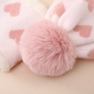 Detail von weichem rosa Herz-Jacquard-Strick und großem Kunstpelz-Pompon für Kinder