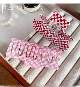 Close-up of red and pink checkered acrylic hair claws in a velvet display box