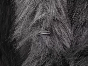 Detail macro shot of dark grey faux fur coat showing soft fiber texture and woven detail