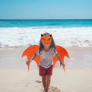 Kids orange bat wings and mask set for Halloween cosplay shown at a scenic beach setting