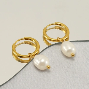 Élégantes boucles d'oreilles vintage dorées avec perles blanches sur surface réfléchissante