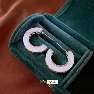 Silver-toned C-shaped hoop earrings with iridescent white shell inlay on green velvet