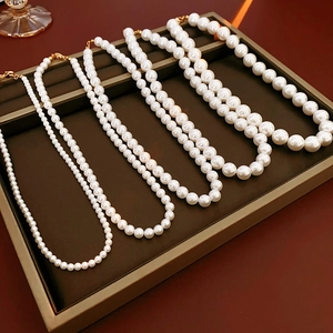 Détail de quatre tailles de colliers de perles blanches avec fermoirs dorés sur plateau