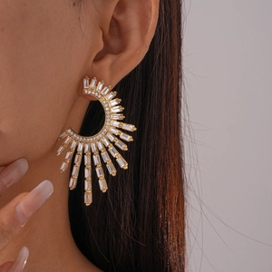 Detailed view of large gold geometric C-shaped fan earring with sparkling crystals on ear