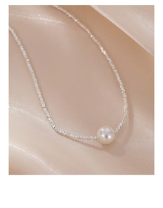 Detailed macro shot of a white pearl pendant on a textured 925 sterling silver chain