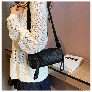 Detailaufnahme einer schwarzen gesteppten Zylindertasche mit breitem Nylonriemen am Modell