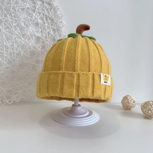 Detailed view of yellow pumpkin knit baby hat featuring green leaf and brown stem detail