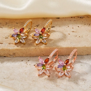 Detailed close-up of lotus flower earrings with multi-color zircons on textured stone