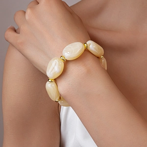 Detail of chunky acrylic marble oval beads with small gold spacers on a woman's wrist