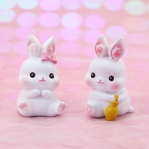 Detail of cute white resin rabbit figurines with pink bows and yellow lucky bag accents