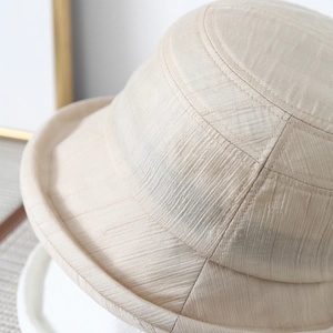 Macro detail of beige bucket hat showing textured pinstripe fabric and reinforced stitching