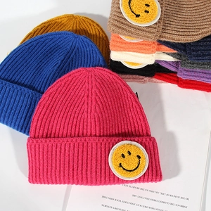 Knitted ribbed beanie hats with yellow smiley face patch in multiple vibrant colors