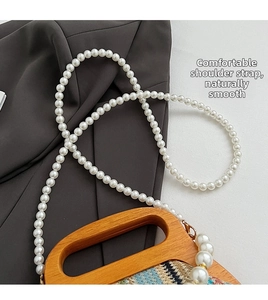 Detail of multi-color woven straw bag featuring round wooden handles and pearl shoulder strap