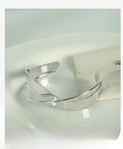 Close-up of silver minimalist double-layer intertwined open bangle on a ceramic plate