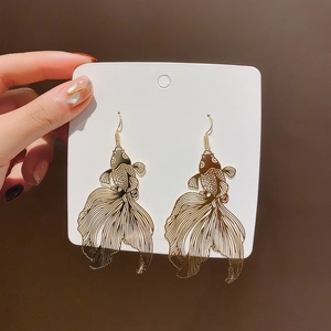 Detail of gold-plated goldfish tassel earrings displayed on a professional jewelry card