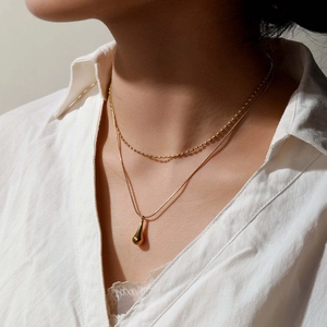 Double-layered gold necklace with water drop pendant on a model wearing white shirt