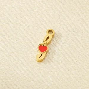 Close-up of golden treble clef pendant with a red heart on beige textured fabric