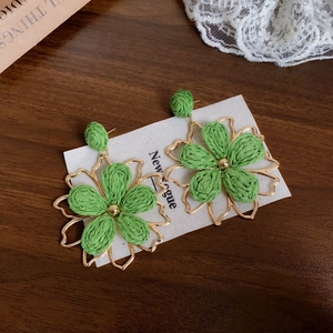 Detail of green raffia flower earrings with gold metal outlines on white display card