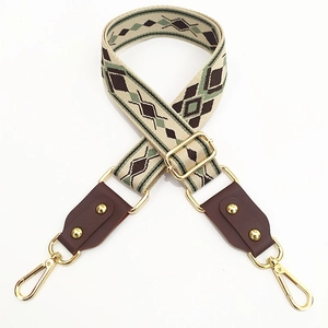 Detail of jacquard woven bag strap with green geometric pattern and leather ends