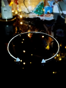 Macro shot of silver choker with sparkling diamonds and blue triangle gemstones