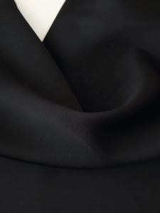 Makroaufnahme von schwarzem Satinstoff mit glatter Textur und weichem Fall des Sets