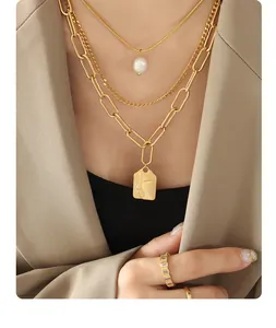 Detail of layered gold necklaces with freshwater pearl and abstract face coin pendant