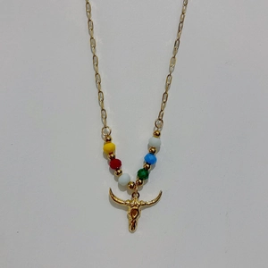 Detailed close-up of golden paperclip chain necklace with colorful beads and bull skull pendant