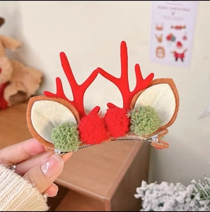 Macro shot of Christmas reindeer antler hair clip with festive red and green pompoms