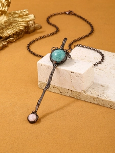 Detail of vintage scepter pendant with amazonite and rose quartz on a white marble cube