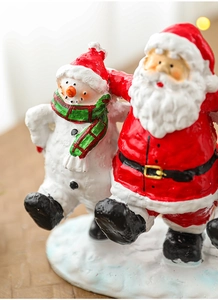Macro detail of resin Santa and Snowman figurines with hand-painted textures and snow base