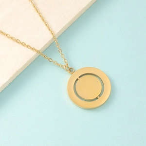 Detail showing the rotatable gold geometric double ring pendant on a stone surface