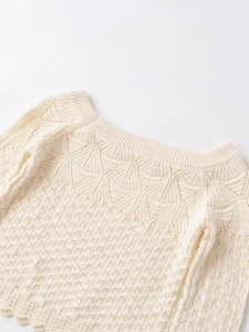 Detail shot of the cream-colored knit top featuring intricate hollow wave and mesh patterns