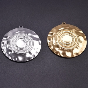 Macro detail of irregular water-ripple round pendants in gold and silver steel finish