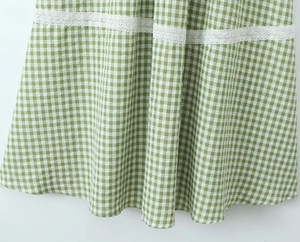 Detailed view of the green checkered hem featuring delicate white lace trim and floral texture