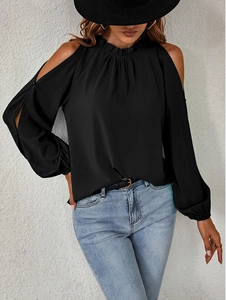 Close-up of black cold-shoulder top featuring ruffle neckline and smocked long sleeves