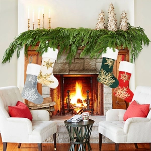 Detail of four Christmas stockings with snowflake embroidery hanging above a warm fireplace