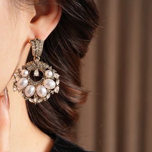 Détail de boucles d'oreilles vintage en or et perles portées par un mannequin