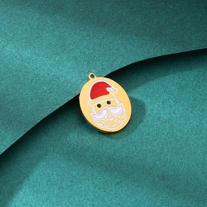 Macro view of a gold oval Santa Claus charm with red enamel details on green background