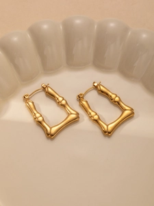 Detailed view of gold titanium earrings with elegant bamboo texture on a ceramic tray