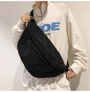 Close-up of black corduroy crossbody bag texture and zipper detail worn by a model