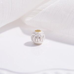 Macro shot of S925 sterling silver beads with sandblasted texture on white silk fabric