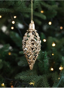 Dettaglio di un ornamento a goccia dorato traforato con rilievo di foglie su un albero di Natale