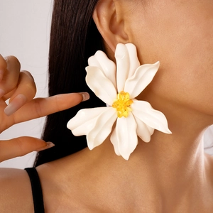 Macro view of oversized white acrylic flower earrings with yellow beaded centers