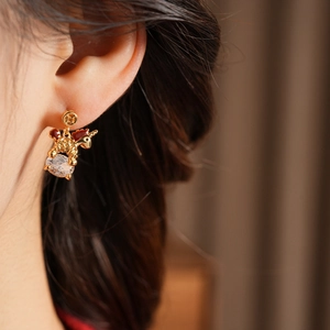 Close-up of model wearing a 18k gold unicorn earring with red enamel and clear zircon