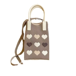 Detailed knit texture of mini phone bag featuring colorful heart patterns and cream strap