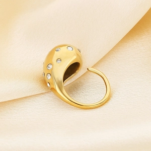 Detailed close-up of a gold waterdrop ring with cubic zirconia on champagne silk fabric